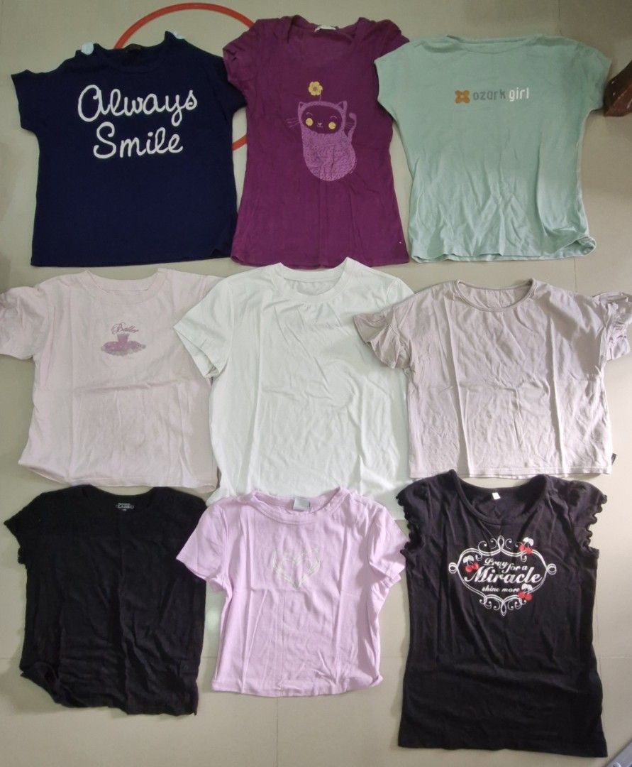 Assorted Graphic T-shirts (Category: Babies & Kids Fashion) located in Malolos. Submitted by prelovedclothes_stuff (Listing ID 1406750314, Image 1). Description: Collection of assorted graphic t-shirts in various colors and designs. Includes shirts with the phrases "Always Smile" and "ozork girl", as well as cat and ballet-themed graphics. Available in black, pink, white, purple, and blue. Sizes and specific brands are not specified..