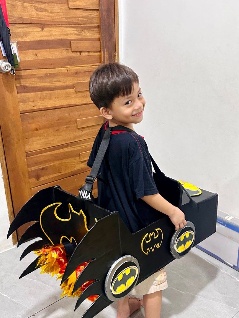 DIY Batman Car Costume (Category: Babies & Kids Fashion) located in Manila. Submitted by AngelResty (Listing ID 1406701984, Image 3). Description: - Handmade Batman car costume - Designed for kids - Features a black car design - Batman logos on wheels and body - Includes a carrying strap - Ideal for dress-up, parties, and Halloween - Made of cardboard.
