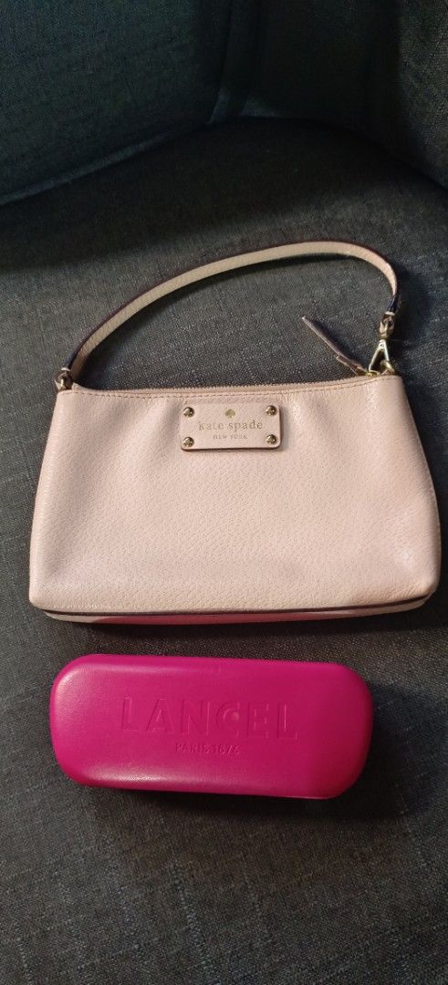 Kate Spade New York Handbag (Category: Luxury Bags & Wallets) located in Muntinlupa City. Submitted by amara211629 (Listing ID 1406712374, Image 1). Description: Kate Spade handbag features a light pink exterior with a top handle and a zipper closure. The interior has a fabric lining with the Kate Spade New York logo. The bag has a small rectangular shape. The bag measures approximately 20cm in length and 13cm in height. It has a detachable strap
