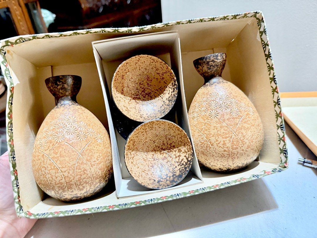 Vintage Sake Set with 2 Bottles and 4 Cups (Category: Coffee & Tea Tableware) located in Rizal. Submitted by caintarizal2024 (Listing ID 1406741337, Image 2). Description: This is a Stoneware Japanese sake set, typically including a flask (tokkuri) and cups (ochoko). The set includes two bottles (tokkuri) and four cups (ochoko) in a gift box. It is crafted from stoneware with a unique, stone-like or “lava ash brown” glaze. The vessels have a subt