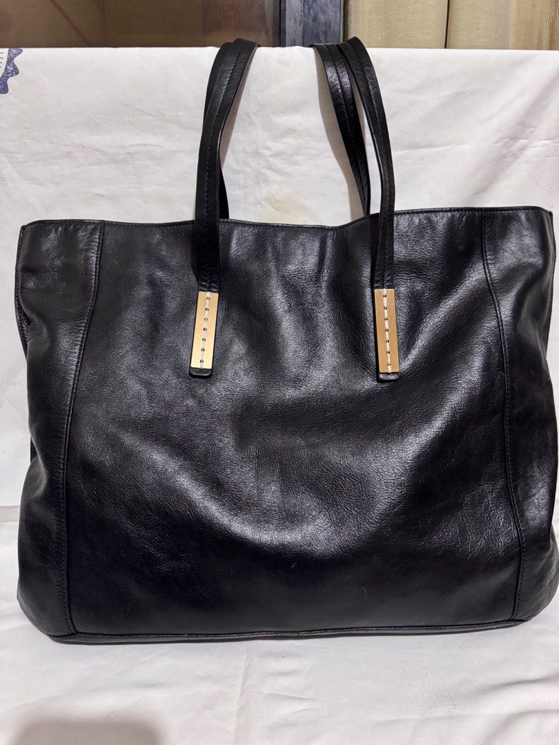 Joy Gryson Black Leather Tote Bag (Category: Tote Bags) located in Makati City. Submitted by tybexpress (Listing ID 1406989328, Image 1). Description: Decluttering! 18”x15” pure leather - Black leather tote bag by Joy Gryson - Gold-toned accents on top handles - Magnetic snap closure - Gray interior lining - Spacious design - Suitable for everyday use - Joy Gryson logo visible.