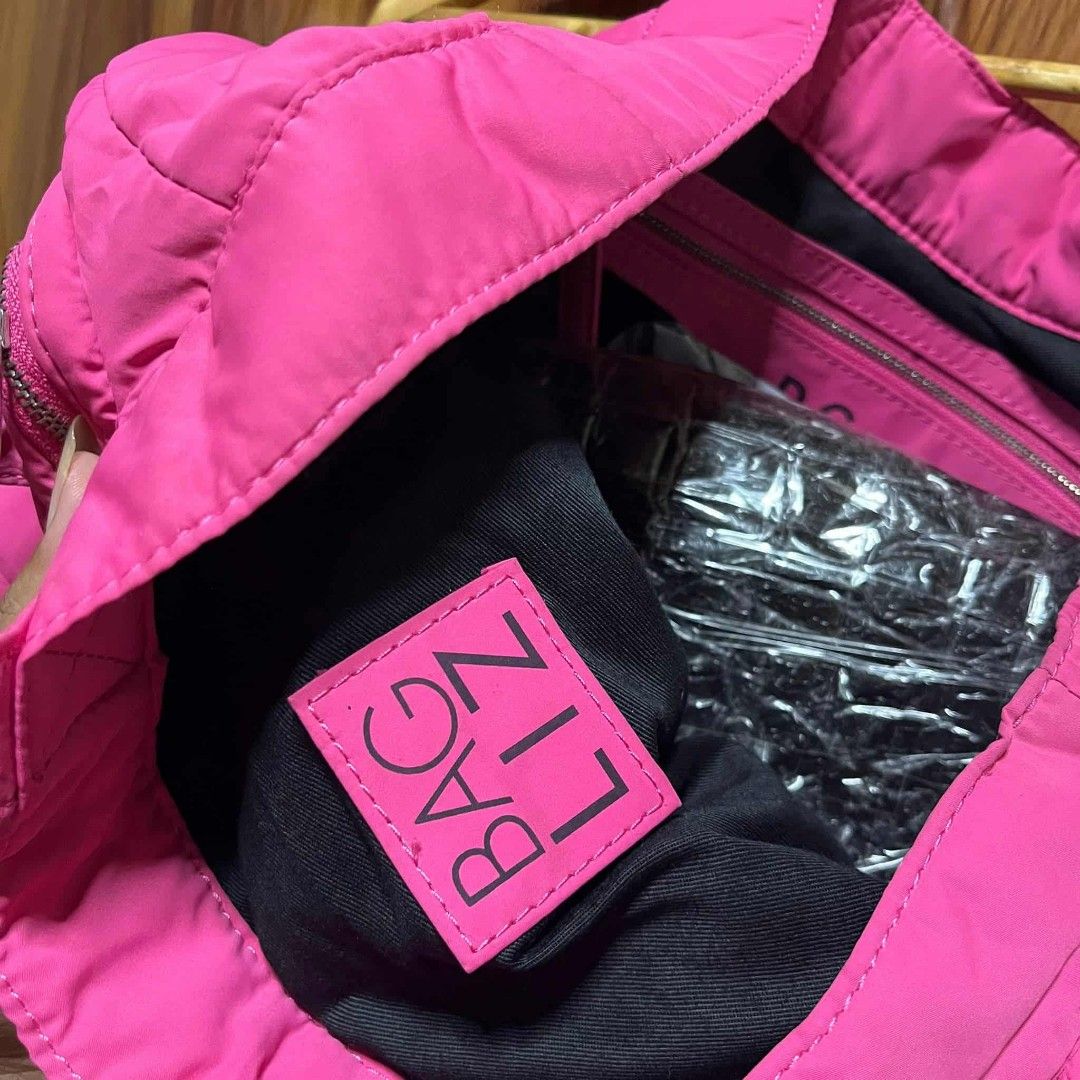 D&G Pink Tote Bag (Category: Luxury Bags & Wallets) located in Carmen. Submitted by ar_thrift00 (Listing ID 1401915539, Image 3). Description: D&G tote bag features a vibrant pink color and multiple exterior pockets with zipper closures. The interior includes a zippered pocket and a brand label. The bag has two top handles for carrying. The D&G logo is visible on the front of the bag..