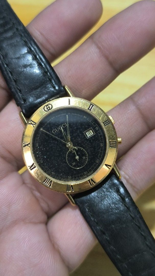 Gucci Gold-Tone Watch with Black Dial (Category: Women's Watches) located in Taguig. Submitted by tester1x (Listing ID 1401946668, Image 3). Description: - Gucci watch with gold-tone case - Sleek black dial - Roman numeral hour markers - Date display - Black leather strap - Gold-tone buckle - Gucci logo and model number 3600J engraved on the back - Features a small subdial.