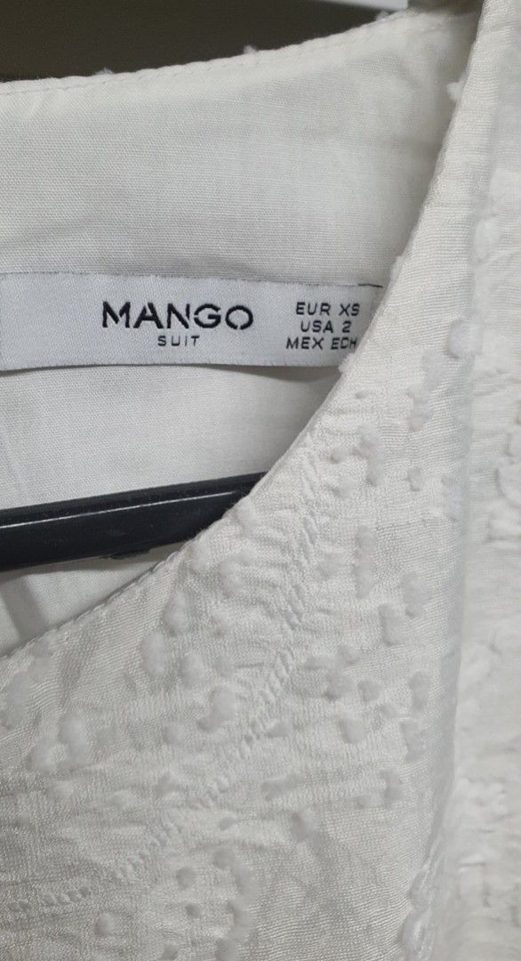 Mango White Sleeveless Dress (Category: Dresses) located in Manila. Submitted by apoltree (Listing ID 1401953496, Image 3). Description: White sleeveless dress from Mango. Features a textured fabric and a simple, elegant design. The dress has a button closure at the back. The label indicates an EUR XS, USA 2, MEX ECH size. Perfect for a casual or semi-formal occasion. Unused but washed RFS - decluttering.