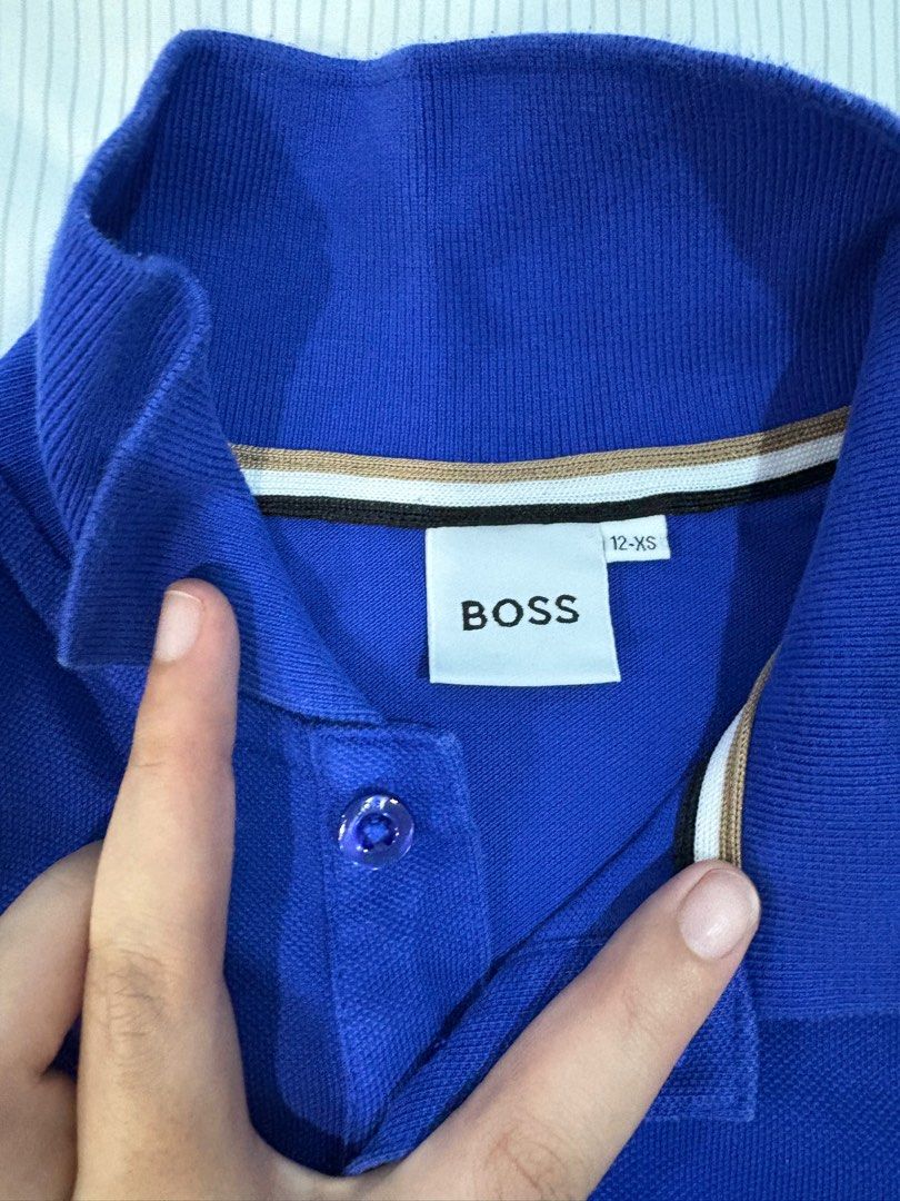 BOSS Blue Polo Shirt (Category: Babies & Kids Fashion) located in Quezon City. Submitted by ccamp17 (Listing ID 1407132676, Image 2). Description: - Brand: BOSS - Color: Vibrant Blue - Style: Polo shirt with high collar and three buttons - Sleeves: Short - Details: Embroidered BOSS logo on chest - Size: 12-XS - Condition: Good.