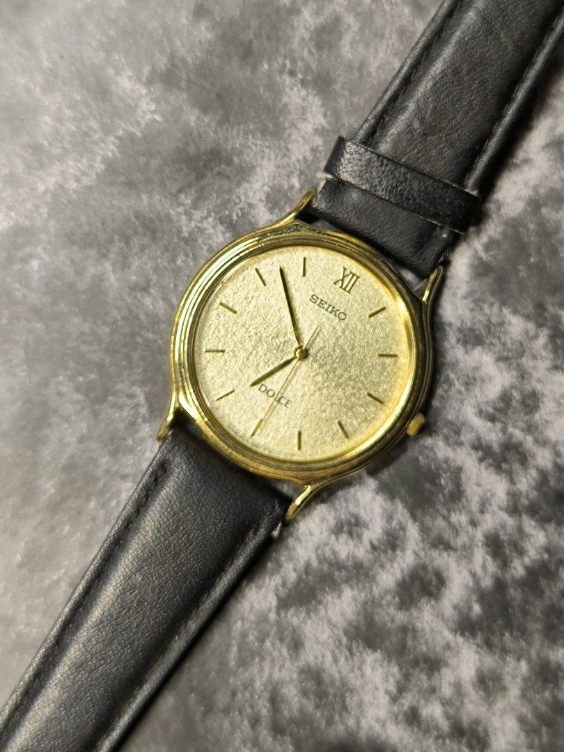 Seiko Dolce Gold Watch (Category: Men's Watches) located in Pasay City. Submitted by cassiuss (Listing ID 1407109847, Image 1). Description: - Seiko Dolce watch - Gold-toned dial - Black leather strap - Gold-colored case - Roman numeral hour markers - Sleek, minimalist design - Suitable for everyday wear or special occasions - 37mm case size - Strap need replacement.