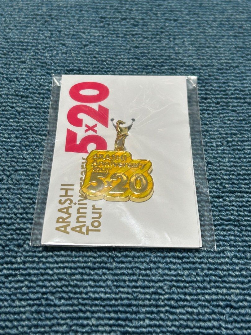 Arashi 5x20 Anniversary Tour Keychain (Category: Vintage Collectibles) located in Angeles City. Submitted by zyeplus (Listing ID 1402166596, Image 1). Description: Arashi 5x20 Anniversary Tour keychain. It features a gold-colored pendant with the words "ARASHI Anniversary Tour 5x20". The keychain is still in its original packaging. The back of the packaging includes Japanese text and a barcode..