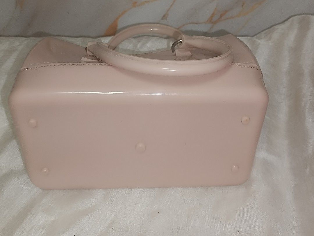 -Pink jelly (Category: Luxury Bags & Wallets) located in Quezon City. Submitted by maeclosetph (Listing ID 1402232560, Image 3). Description: Pink Furla Candy Bag with a top handle and a zip closure. The bag has a rectangular shape with rounded edges. The bag has a glossy finish. The bottom of the bag has small feet..