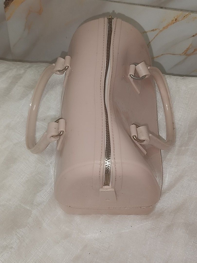 -Pink jelly (Category: Luxury Bags & Wallets) located in Quezon City. Submitted by maeclosetph (Listing ID 1402232560, Image 2). Description: Pink Furla Candy Bag with a top handle and a zip closure. The bag has a rectangular shape with rounded edges. The bag has a glossy finish. The bottom of the bag has small feet..