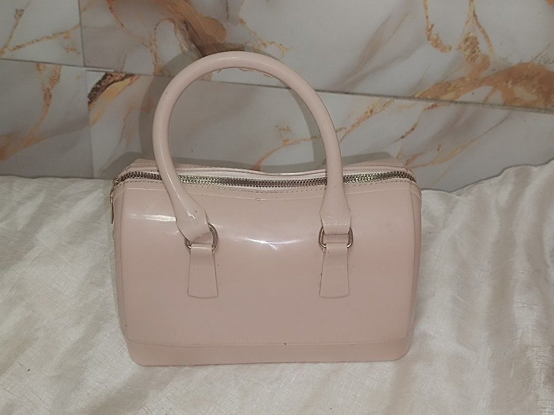 -Pink jelly (Category: Luxury Bags & Wallets) located in Quezon City. Submitted by maeclosetph (Listing ID 1402232560, Image 1). Description: Pink Furla Candy Bag with a top handle and a zip closure. The bag has a rectangular shape with rounded edges. The bag has a glossy finish. The bottom of the bag has small feet..