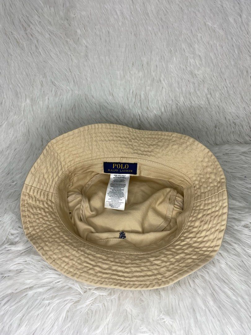Polo Ralph Lauren Bucket Hat (Category: Caps & Hats) located in Batangas. Submitted by lifehitz.ph (Listing ID 1402255810, Image 2). Description: Polo Ralph Lauren bucket hat is a classic accessory. It features the iconic polo player logo. The hat is a neutral beige color. The interior has a tag with the Polo Ralph Lauren branding..