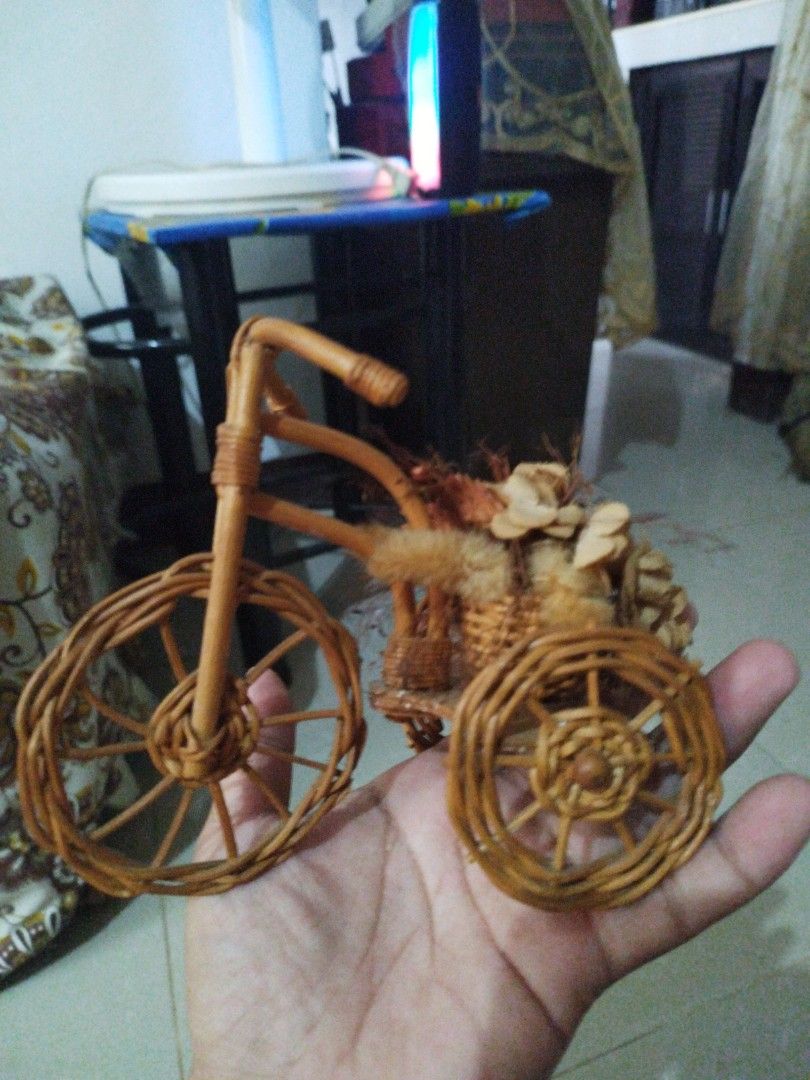 Wicker Tricycle with Floral Basket (Category: Motorbikes for Sale) located in Abucay. Submitted by jflshoppe1989 (Listing ID 1402285950, Image 3). Description: Decorative tricycle is made of woven wicker. It features a small basket filled with dried flowers and decorative elements. The tricycle has three wheels and a handlebar. It is a charming piece that can be used as a decorative item or a unique display piece..