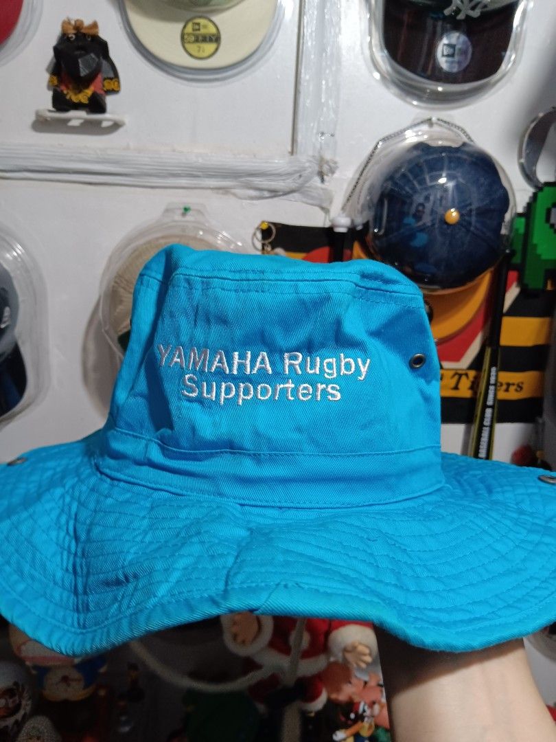 Yamaha Rugby Supporters Bucket Hat (Category: Caps & Hats) located in Manila. Submitted by roshisneakerhouse (Listing ID 1402123947, Image 2). Description: Blue bucket hat featuring the Yamaha logo and "Yamaha Rugby Supporters" text. It has a brim and eyelets for ventilation. The hat is made of 100% cotton and manufactured in China. The inside of the hat has a light grey lining and a drawstring. The hat is a vibrant blue color. Good as new No iss