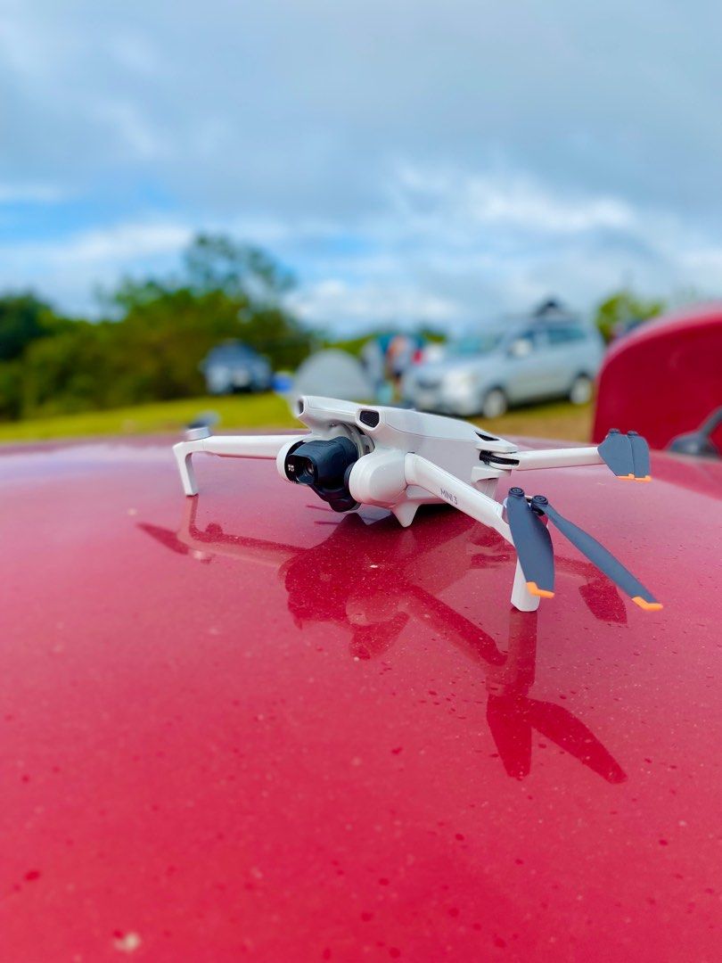 DJI Mini 3 Drone [FOR RENT] (Category: Drones) located in Manila. Submitted by purelion-536c (Listing ID 1402342493, Image 1). Description: FOR RENT DJI Mini 3 drone with remote controller. The drone is white and gray. The remote controller has a phone holder. The drone is shown in use, with the controller displaying the live feed. The drone has its propellers attached and is ready to fly. The drone is shown outdoors and indoors. Equipment Rented