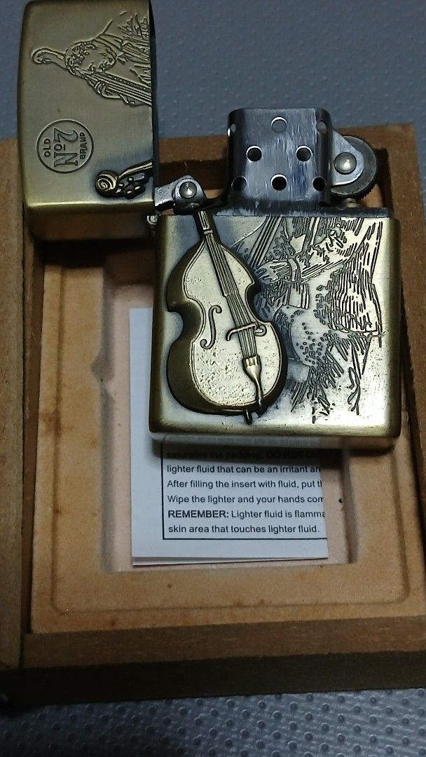 1996 Star JazzJack Daniel's Zippo style Lighter (Category: Vintage Collectibles) located in Quezon City. Submitted by mrs.maria (Listing ID 1402427701, Image 3). Description: "1996 Star Jazz" Jack Daniel's Zippo style lighter features a unique design with a musical instrument motif. It comes in its original box, which also features the Jack Daniel's branding. The lighter has an antique brass finish. The box includes a small instruction card. The 
