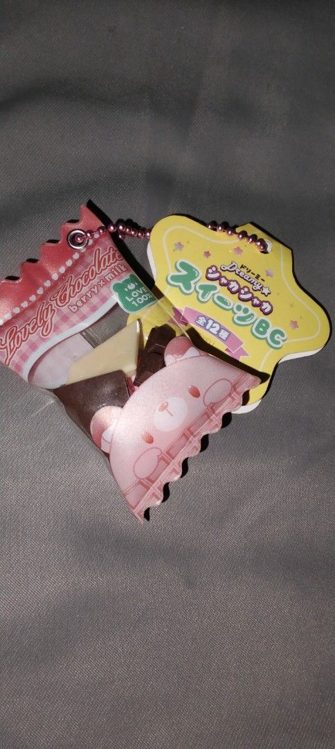 Lovely Chocolate Keychain (Category: Charms) located in Santa Rosa. Submitted by animemerchcollection (Listing ID 1402374825, Image 1). Description: - Adorable chocolate-themed keychain. - Includes a pink bear-shaped charm. - Features a yellow tag with Japanese text. - Attached to a stylish beaded chain. - Perfect accessory for your bag or keys!.