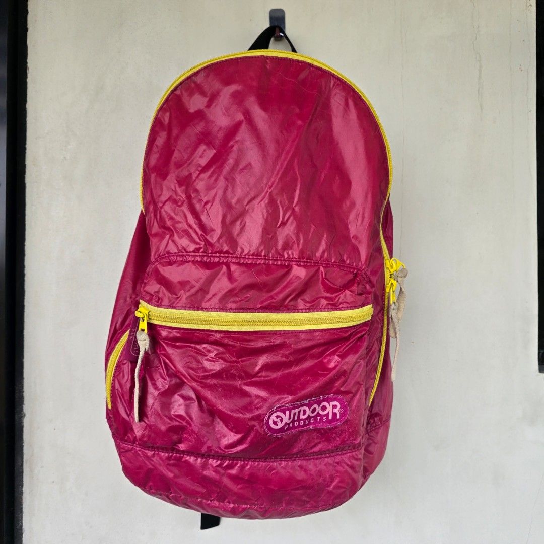 Outdoor Products Packable Backpack (Category: Backpacks) located in Macabebe. Submitted by pampanga_chic (Listing ID 1402316097, Image 1). Description: vibrant pink backpack with yellow zippers. It features a main compartment and a front pocket, both with zippers. The backpack has adjustable shoulder straps and a mesh back panel for comfort. It also has a small interior pocket. The backpack is packable and can be folded for easy storage. please r