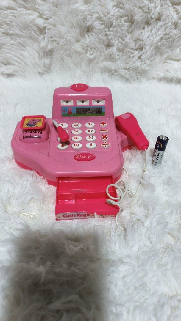 Pink Toy Cash Register (Category: Kids Toys) located in Marikina City. Submitted by andreah_16 (Listing ID 1402289444, Image 1). Description: - Pink toy cash register - Features a calculator, scanner, and cash drawer - Includes a toy microphone - Small display screen - Adorned with a Peppa Pig sticker - Comes with a battery.