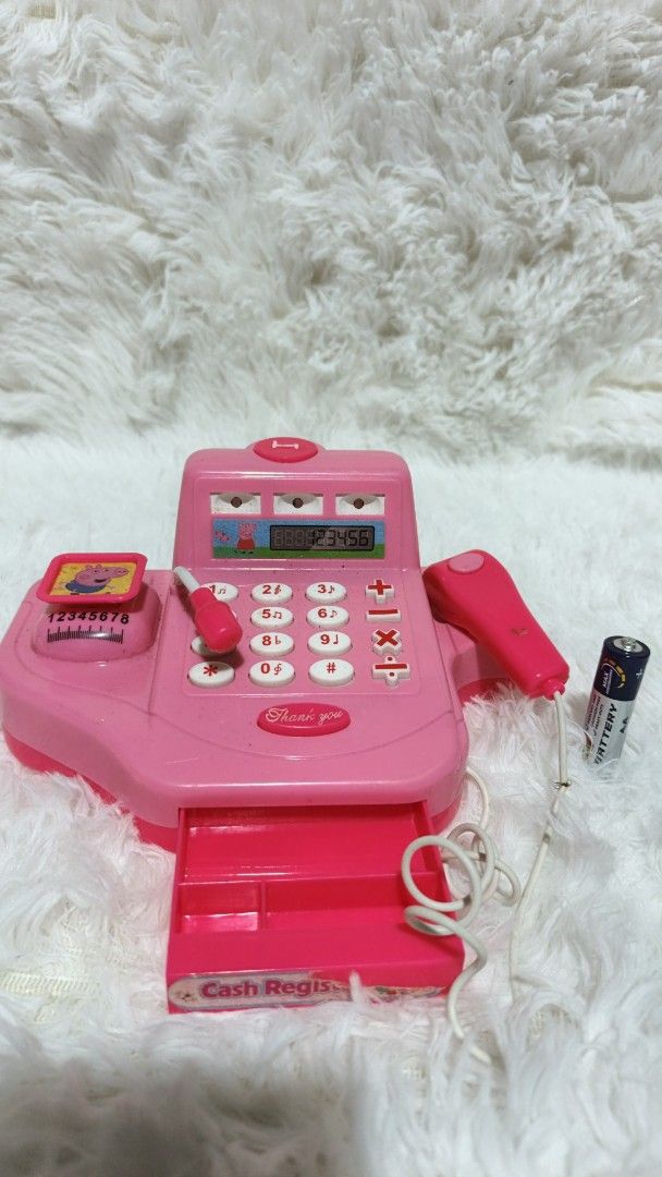 Pink Toy Cash Register (Category: Kids Toys) located in Marikina City. Submitted by andreah_16 (Listing ID 1402289444, Image 2). Description: - Pink toy cash register - Features a calculator, scanner, and cash drawer - Includes a toy microphone - Small display screen - Adorned with a Peppa Pig sticker - Comes with a battery.