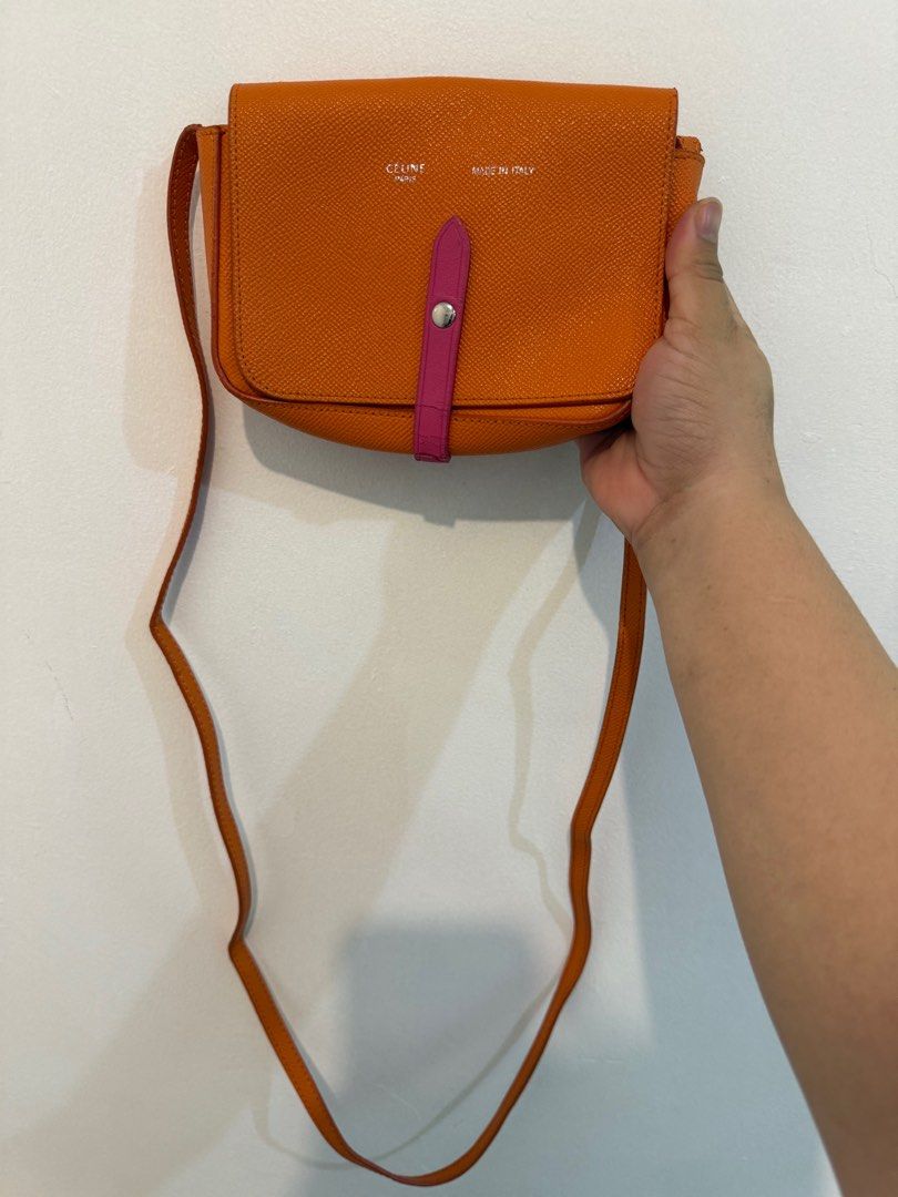 Celine Orange Crossbody Bag (Category: Luxury Bags & Wallets) located in Marikina City. Submitted by robicamz (Listing ID 1402517104, Image 2). Description: Authentic Orange crossbody bag with a pink strap. (Very cutesy) Features the Celine Paris logo and "Made in Italy" inscription. The bag has a flap closure and a long strap. The pink strap shows some wear and tear (see last photo) Slightly negotiable.