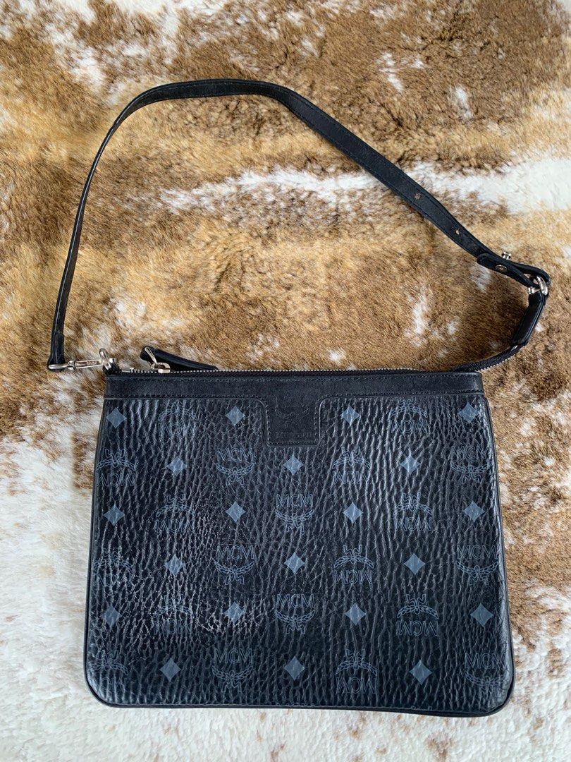 MCM Black Clutch with Strap (Category: Luxury Bags & Wallets) located in Manila. Submitted by _.d4awnn (Listing ID 1402502538, Image 1). Description: - Authentic MCM clutch - Features the classic MCM logo pattern - Includes a detachable black strap - Interior with black and white checkered pattern - Secure zipper closure - Made in Korea - Hardware engraved with the MCM logo.