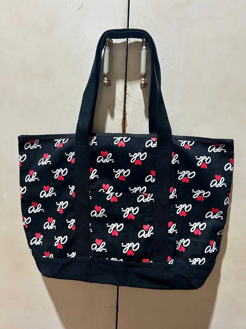 Agnes B. Voyage Tote Bag (Category: Tote Bags) located in Quezon City. Submitted by asiaco (Listing ID 1402727017, Image 1). Description: Black Agnes B. Voyage tote bag with a repeating logo and heart pattern. Features a front pocket and sturdy black handles. The bag measures approximately 38 cm in width. The interior includes a tag with Japanese text. Perfect for everyday use..