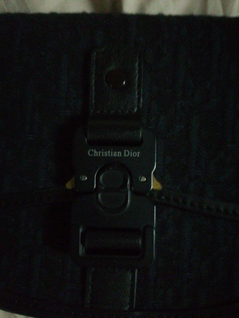 Christian Dior Saddle Bag (Category: Luxury Bags & Wallets) located in Makati City. Submitted by divimall9928169 (Listing ID 1402716032, Image 1). Description: Black Christian Dior saddle bag. Features a flap closure with a metal buckle engraved with the brand name. The bag has a shoulder strap and a patterned exterior. The interior is black..