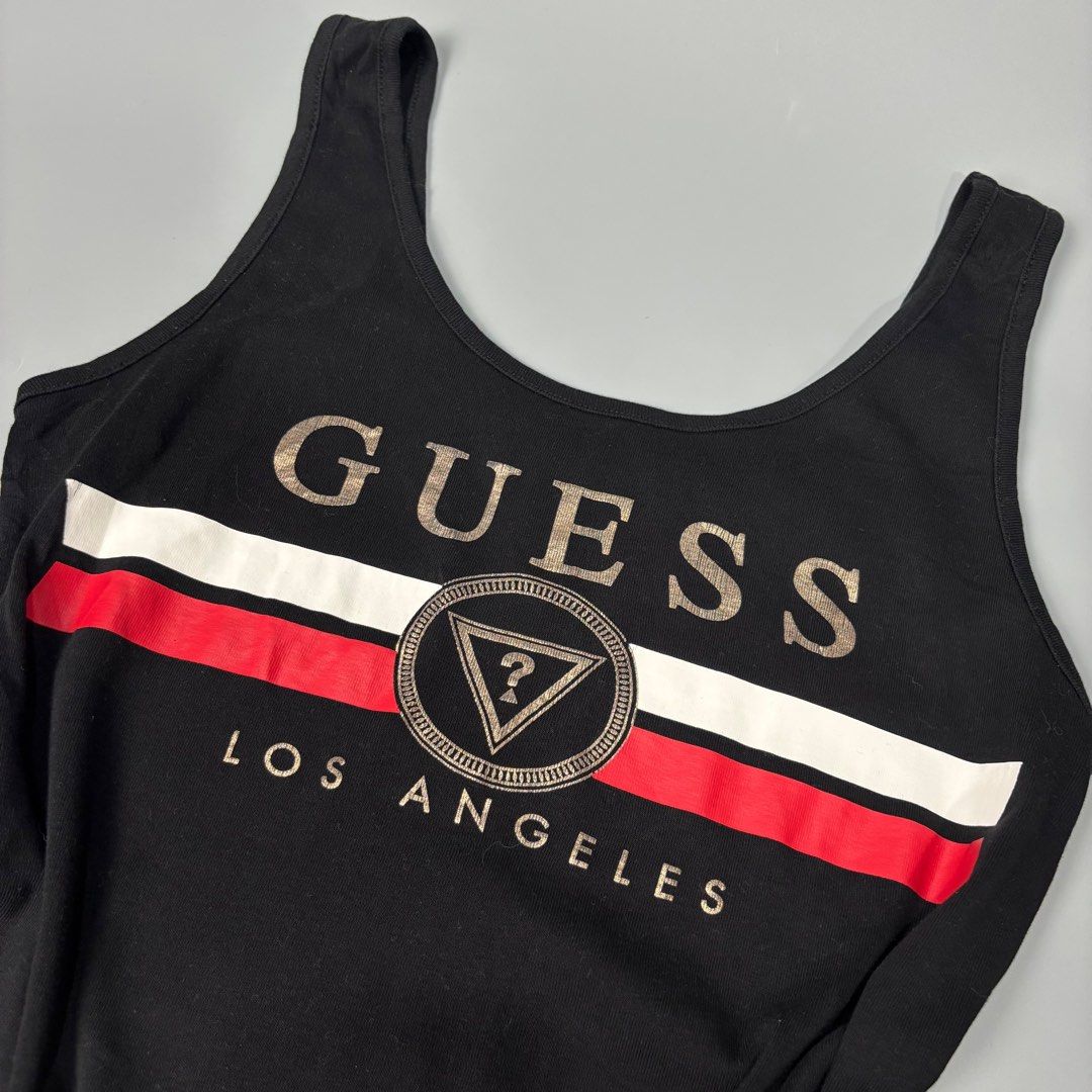 Guess Los Angeles Tank Top (Category: Sleeveless) located in Angeles City. Submitted by tey68 (Listing ID 1402800940, Image 2). Description: Black Guess tank top with a bold Guess logo and 'Los Angeles' print. Features a red and white stripe design across the chest. The tag indicates it is made in Bangladesh and available in sizes XS, S, M, and L. The tank top has a scoop neck and a fitted silhouette..