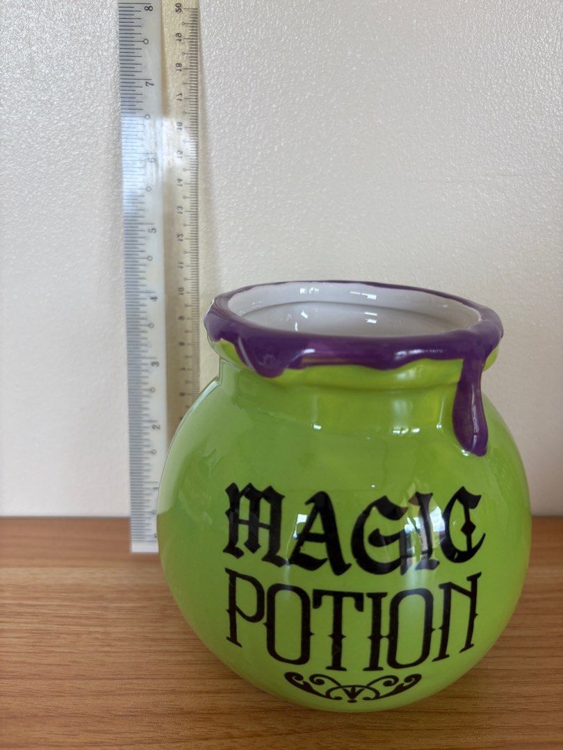 Magic Potion Pot (Category: Cookers) located in Antipolo. Submitted by anabri (Listing ID 1402732854, Image 2). Description: - Green ceramic pot - Features "MAGIC POTION" text - Purple dripping rim design - Round shape - Ideal for Halloween decor or as a unique container.