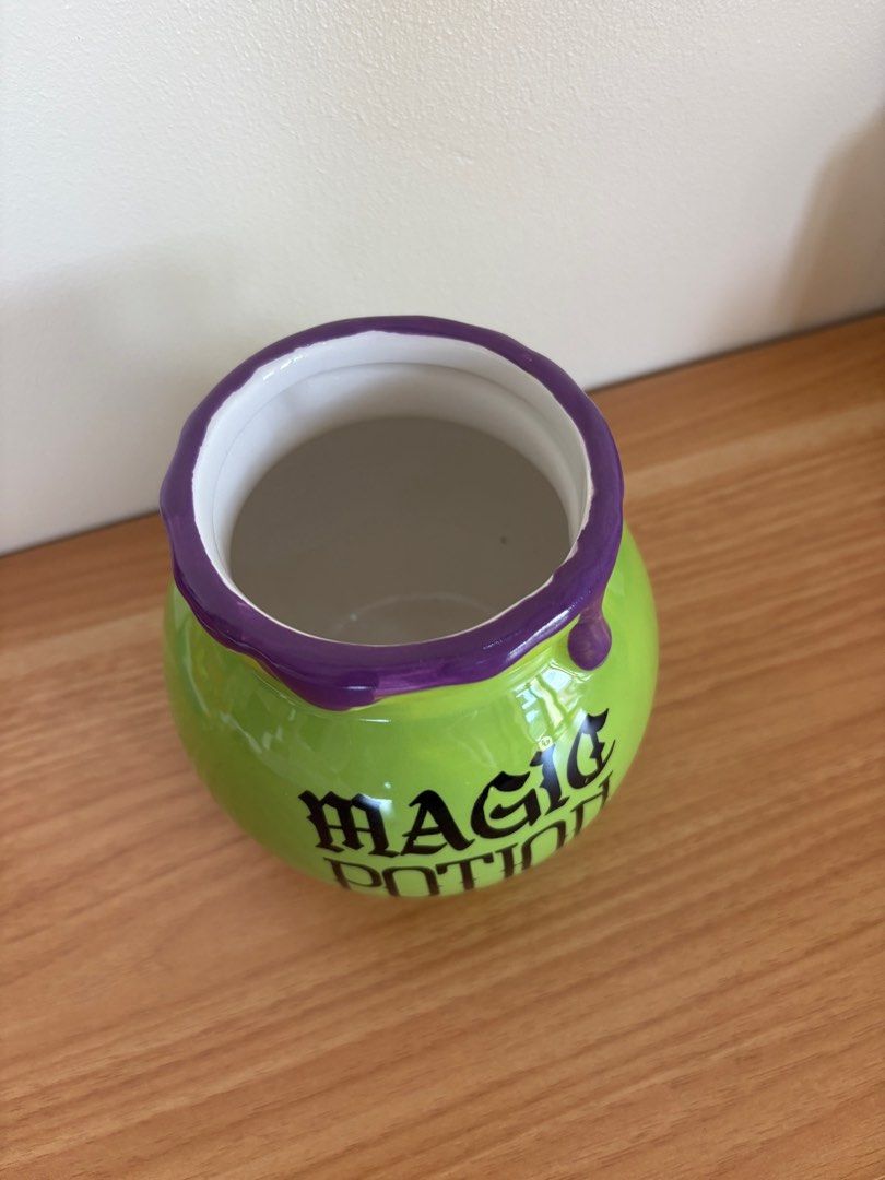 Magic Potion Pot (Category: Cookers) located in Antipolo. Submitted by anabri (Listing ID 1402732854, Image 3). Description: - Green ceramic pot - Features "MAGIC POTION" text - Purple dripping rim design - Round shape - Ideal for Halloween decor or as a unique container.