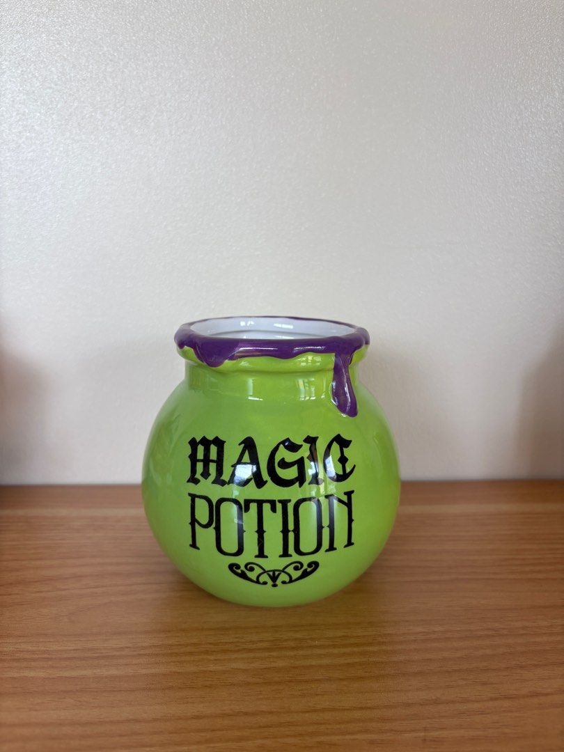Magic Potion Pot (Category: Cookers) located in Antipolo. Submitted by anabri (Listing ID 1402732854, Image 1). Description: - Green ceramic pot - Features "MAGIC POTION" text - Purple dripping rim design - Round shape - Ideal for Halloween decor or as a unique container.