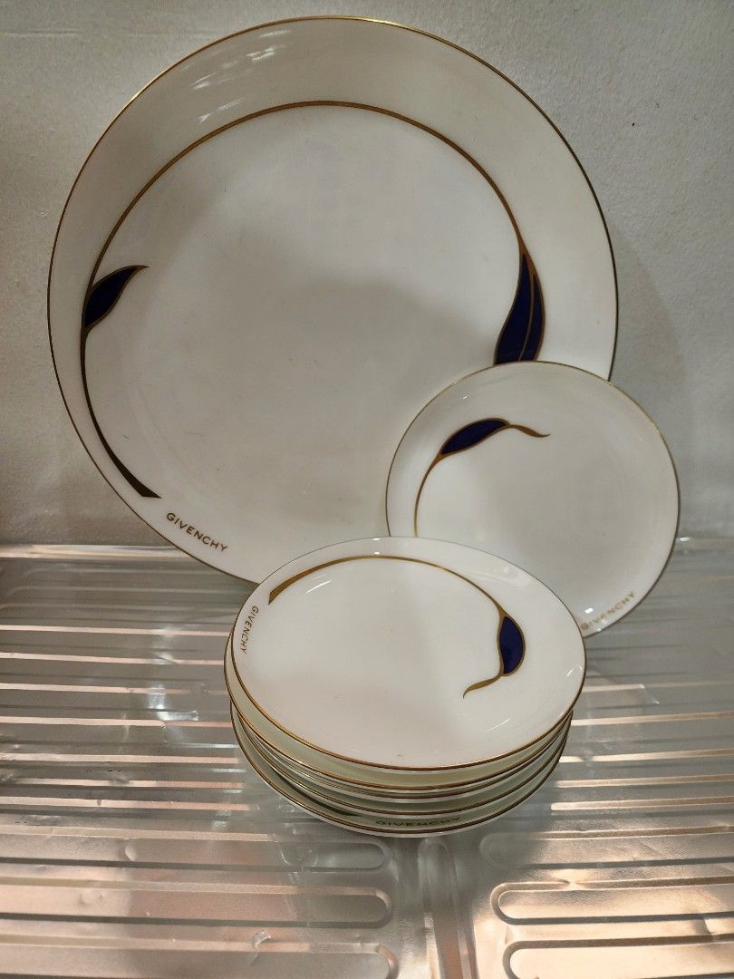 Givenchy Porcelain Plate Set (Category: Dinnerware & Cutlery) located in Pasay City. Submitted by amine_antiguo (Listing ID 1402890114, Image 1). Description: Elegant Givenchy porcelain plate set. Features a white base with gold trim and a distinctive navy blue leaf design. Includes various plate sizes, perfect for serving different courses. The plates are marked with the Givenchy brand name. A stylish addition to any dining collection..