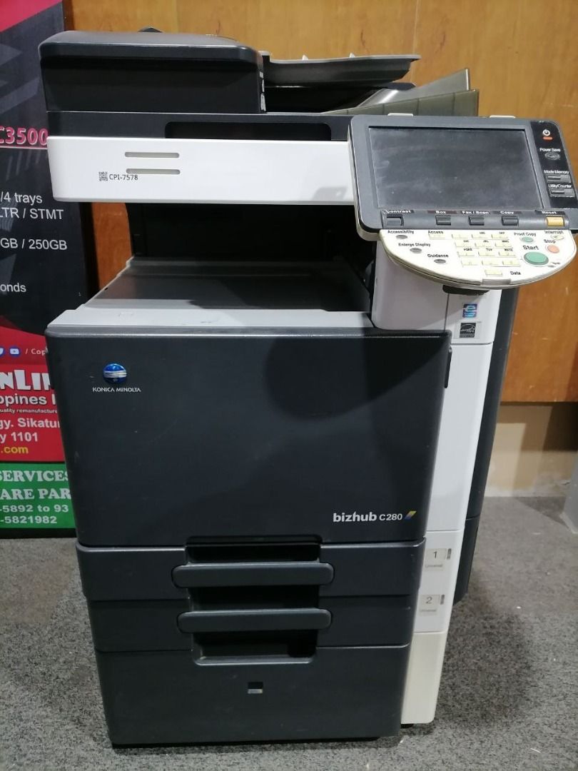 Konica Minolta Bizhub C280 Copier (Category: Printers, Scanners & Copiers) located in Quezon City. Submitted by copieronlineinc (Listing ID 1402868244, Image 1). Description: - Konica Minolta Bizhub C280 color copier - Features a user-friendly control panel and display screen - Equipped with multiple paper trays for efficient printing - Sleek black and white design - Model number clearly visible.