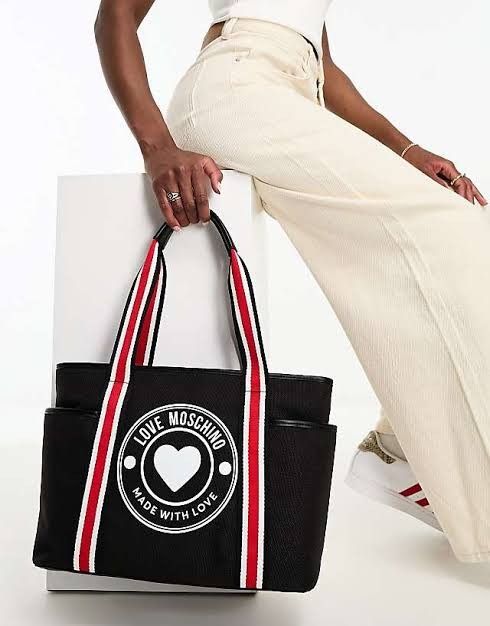 Love Moschino Black Tote Bag (Category: Tote Bags) located in Bacoor. Submitted by msschchc (Listing ID 1403003689, Image 1). Description: - Love Moschino tote bag - Black color - White heart logo with "LOVE MOSCHINO MADE WITH LOVE" - Red and white striped handles - Two side pockets - Perfect for everyday use.
