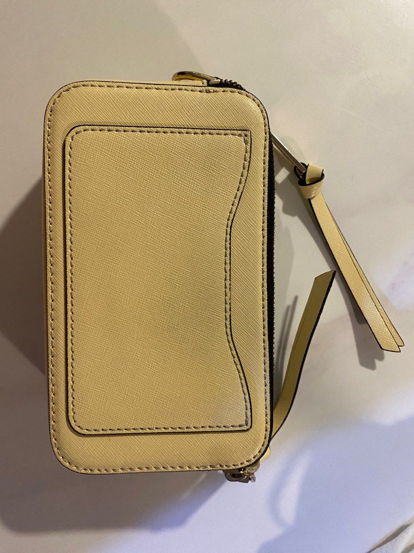 Marc Jacobs The Snapshot Crossbody Bag (Category: Luxury Bags & Wallets) located in Quezon City. Submitted by harleys_stuff (Listing ID 1403011368, Image 2). Description: Marc Jacobs Snapshot crossbody bag features a pale yellow body with a gold-tone logo and hardware. It includes a detachable, striped shoulder strap / guitar strap with gold clasps. The bag has a zip closure. The interior is black. The brand name is visible on the zipper pull and