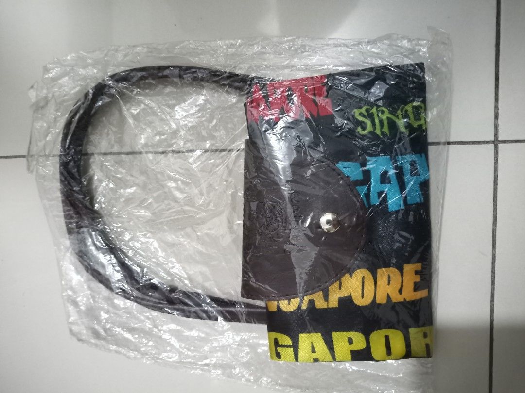 Singapore Souvenir Handbag (Category: Luxury Bags & Wallets) located in Makati City. Submitted by psalm23 (Listing ID 1403006532, Image 2). Description: Get 2 for 900! Handbag features a design with the word "Singapore" printed all over. It has a flap closure and a handle. The bag is still in its original packaging. The bag is black with colorful text and a black handle..
