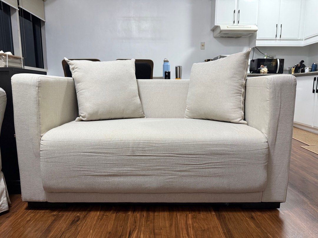 Cream-colored 2-seater Sofa (Category: Sofas) located in Makati City. Submitted by ochie0218 (Listing ID 1407208599, Image 2). Description: - Cream-colored 2-seater sofa - Ideal for small spaces - Includes two matching square pillows - Simple, modern design - Sturdy frame and comfortable cushions.