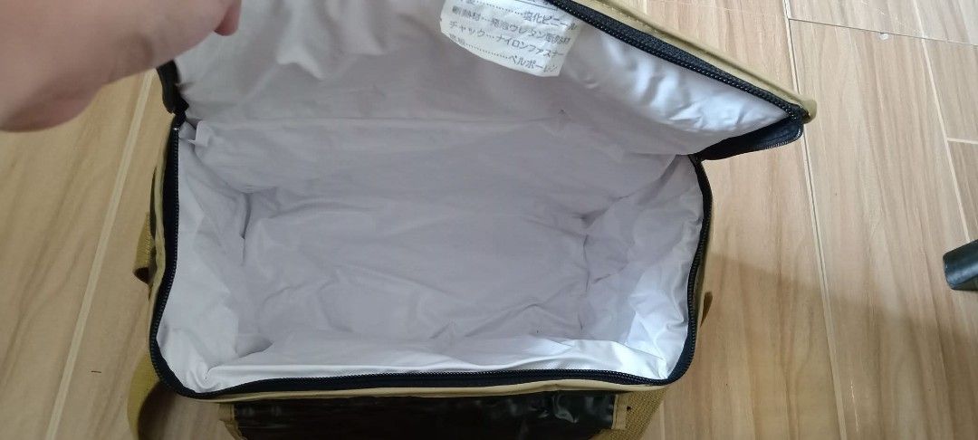 Insulated Cooler Bag with Shoulder Strap (Category: Food Organization & Storage) located in Gapan. Submitted by montesnora80204 (Listing ID 1407319172, Image 3). Description: Insulated cooler bag features a black exterior with a beige trim and strap. It has a front pocket with two button closures. The bag is designed for outdoor activities like mountain climbing, bird watching, and picnics. The interior is white. It includes a top handle and a sh