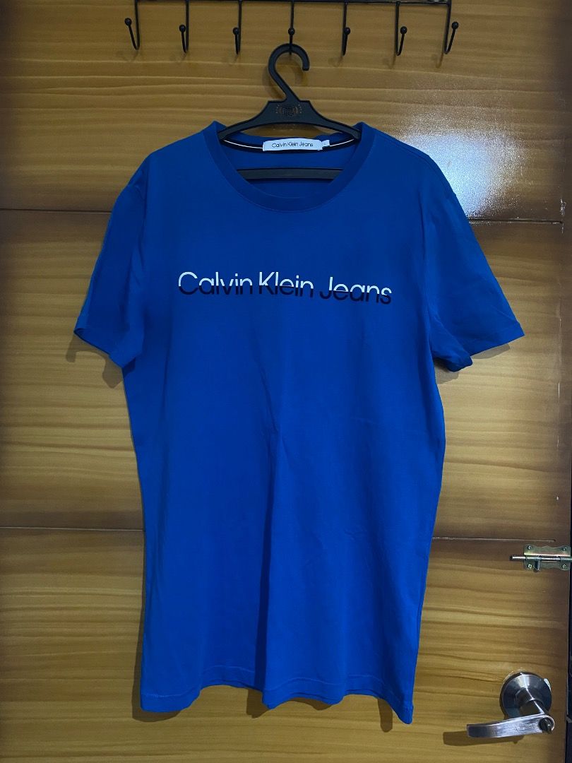 Calvin Klein Jeans Blue T-shirt (Category: Shirts) located in San Fernando. Submitted by love.declutter2 (Listing ID 1408964518, Image 1). Description: - Calvin Klein Jeans T-shirt - Orig - no flaws.