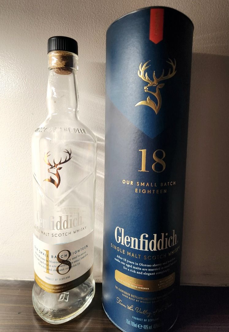 Glenfiddich 18 EMPTY bottle (Category: Beverages) located in Makati City. Submitted by abl320 (Listing ID 1408998427, Image 2). Description: Glenfiddich 18 Year Old Single Malt Scotch Whisky. This bottle is from the small batch series. It is a product of Scotland. The bottle is accompanied by its original packaging. The packaging is a dark blue cylinder with gold lettering and a deer logo. The bottle has a clear glass body with a gold label..