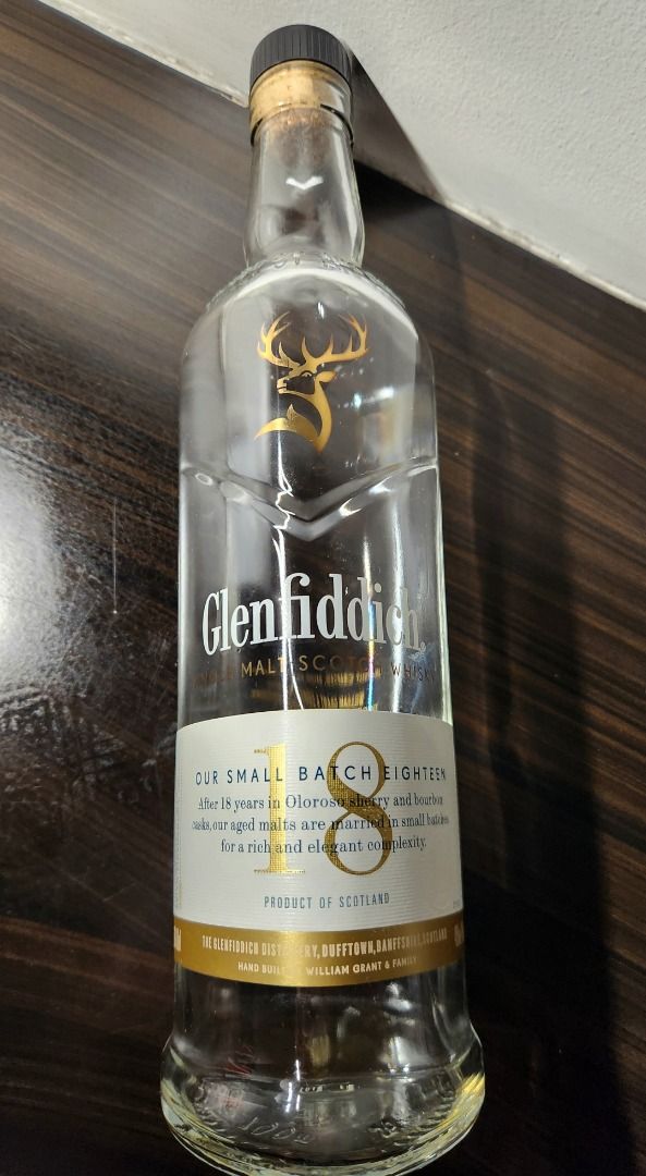 Glenfiddich 18 EMPTY bottle (Category: Beverages) located in Makati City. Submitted by abl320 (Listing ID 1408998427, Image 1). Description: Glenfiddich 18 Year Old Single Malt Scotch Whisky. This bottle is from the small batch series. It is a product of Scotland. The bottle is accompanied by its original packaging. The packaging is a dark blue cylinder with gold lettering and a deer logo. The bottle has a clear glass body with a gold label..