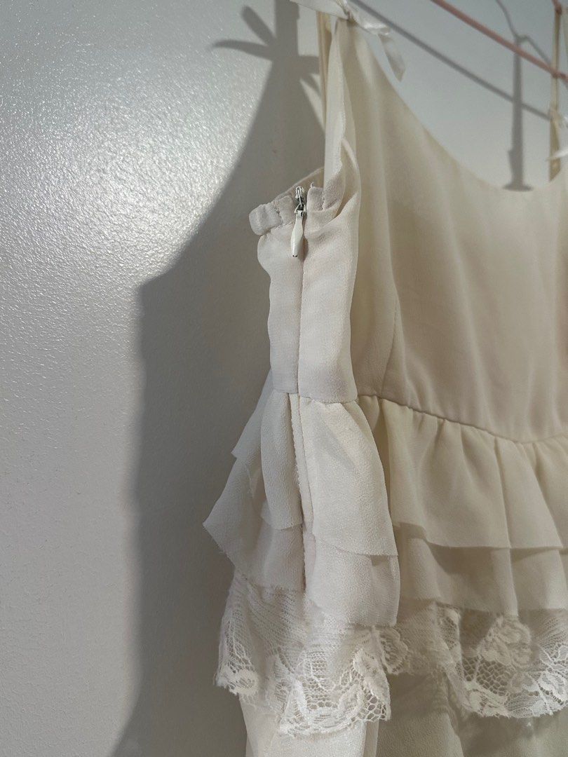ivory/cream tiered ruffle top (Category: Sleeveless) located in Quezon City. Submitted by pur6ing (Listing ID 1408959727, Image 2). Description: - FITS S-L - thrifted this/no brand - lace detail, tiered hems - side zippers (see 2nd pic) - bow detail on strap - a-line top very babygirl/coquette u alr know.