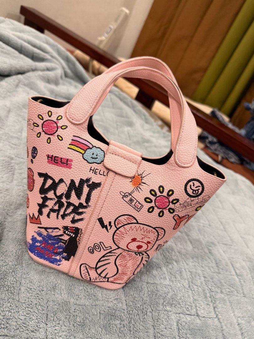 Pink Graffiti Tote Bag with Inner Pouch (Category: Tote Bags) located in Lipa City. Submitted by Msjhen (Listing ID 1408889978, Image 2). Description: From japan. Pink tote bag features a unique graffiti design with a teddy bear and other illustrations. It has two handles and includes a detachable inner pouch with a zipper. The bag has a magnetic closure. The interior is black. The bag is perfect for everyday use..