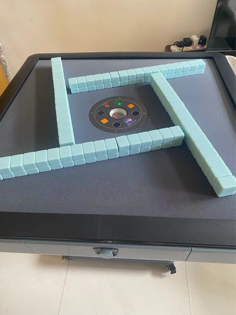 Automatic Mahjong Table （分類：互動玩具）位於 Hong Kong。 由 phrenia 提交（商品編號 1409086263，圖片 3）。簡介： Automatic mahjong table with a grey playing surface and black trim. The table has a central tile-shuffling mechanism and a built-in drawer. It is supported by a pedestal base with wheels for easy movement. Includes a set of light blue mahjong tiles. Original price $5xxx.。