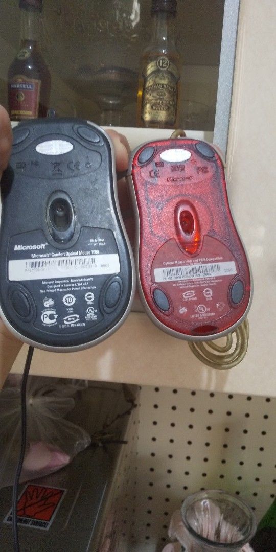 Microsoft Comfort Optical Mouse Package (as-is) (Category: Mouse & Mousepads) located in Carmona. Submitted by rpute (Listing ID 1409071943, Image 3). Description: Two Microsoft Comfort Optical Mouse 1000. One mouse has a black body with a silver trim, and the other has a red body. Both have a scroll wheel and a USB connection. The black mouse has a black cable, while the red mouse has a yellow cable. Both mice are in working condition..