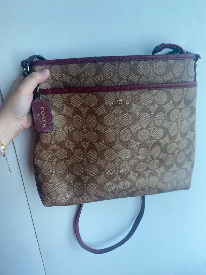 Coach Signature Crossbody Bag (Category: Luxury Bags & Wallets) located in Pasig City. Submitted by angelaaaj (Listing ID 1409314601, Image 1). Description: - Coach crossbody bag - Signature pattern - Burgundy trim and strap - Includes Coach hangtag - Features front pocket and main compartment - Minor scuff on trim.