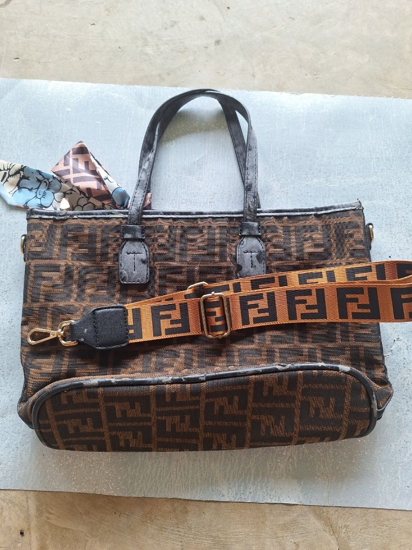 Fendi Tote Bag with Scarf and Strap (Category: Luxury Bags & Wallets) located in Malaybalay. Submitted by mags_sofia (Listing ID 1409381360, Image 1). Description: Dimensions: 14" × 4" × 9.5" Material: - gold brass tone hardware - clothed exterior and interior - has black leather accent for edges, handles, and brand tag - detachable strap and a scarf - top handle and a zipper closure. Compartment: - main compartment has 1 slot pockets and 1 zippe