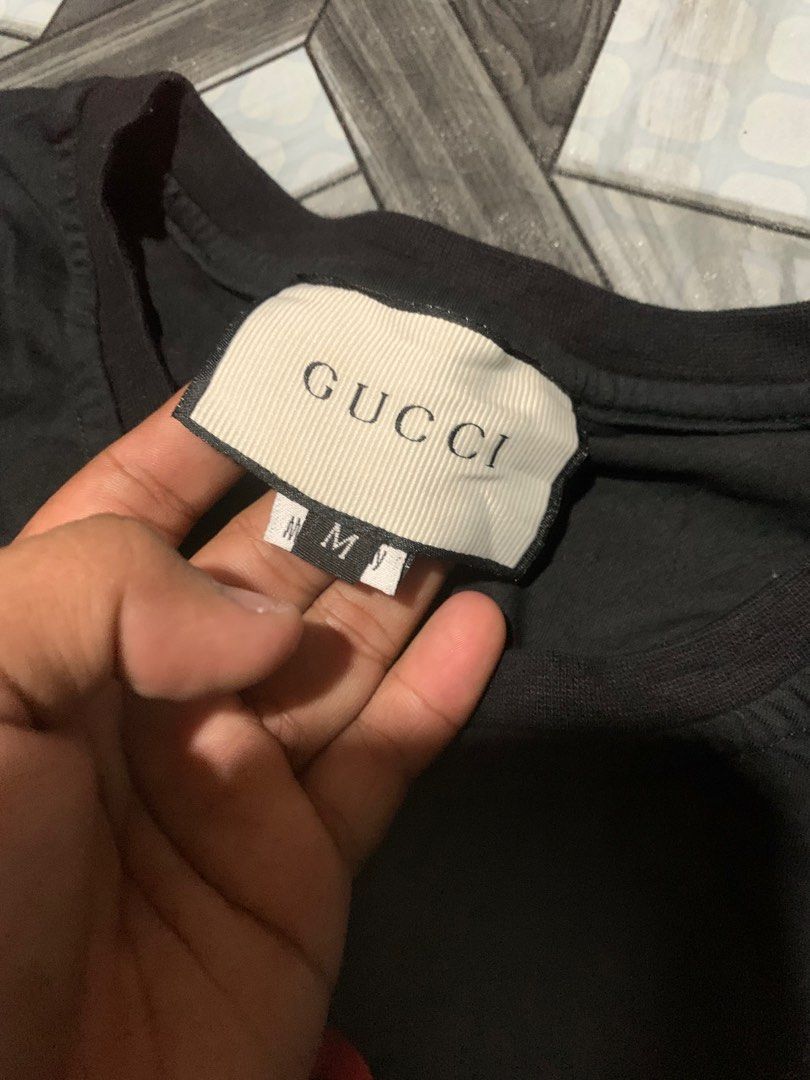 Gucci 'Guccify Yourself' Snake Tee (Category: Luxury Apparel) located in Cagayan de Oro. Submitted by agboysalis60090 (Listing ID 1409352903, Image 2). Description: Authentic Gucci t-shirt featuring the 'Guccify Yourself' graphic with a snake design. The shirt is black with red lettering and a red snake graphic. It is made in Italy and has a size M label. The shirt has the Gucci logo on the tag..