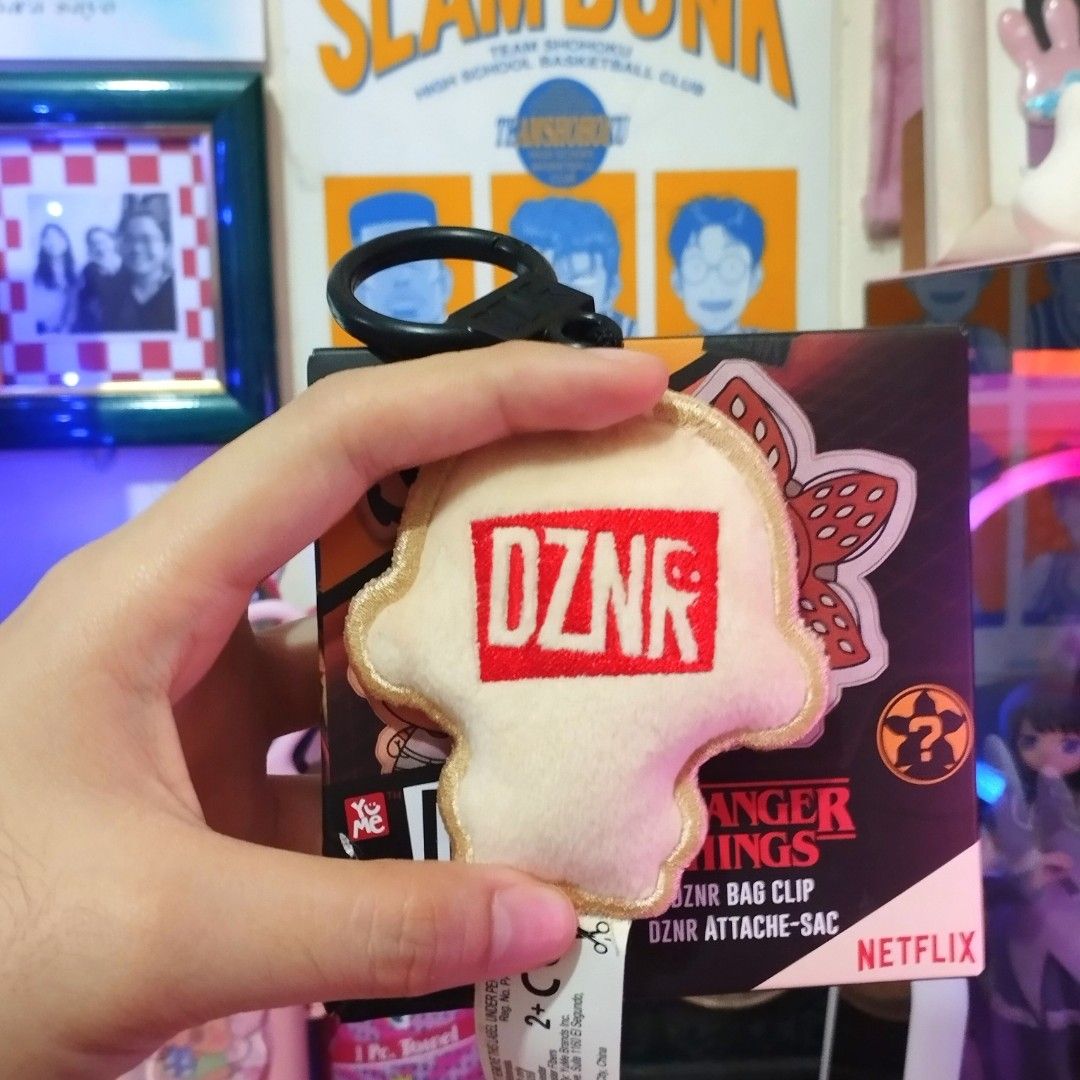 Stranger Things DZN Bag Clip Eleven (Category: Western Merchandise) located in Santa Rosa. Submitted by ayi.yo (Listing ID 1409407078, Image 2). Description: - Stranger Things DZN bag clip featuring Eleven. - Includes a black ring clip for easy attachment. - Brand new, still in original packaging. - Features the Netflix logo. - DZN logo visible on the back..