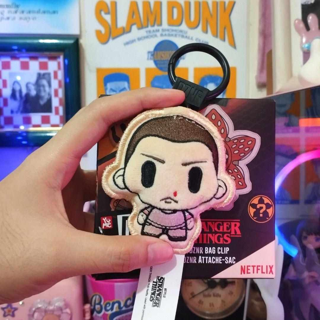 Stranger Things DZN Bag Clip Eleven (Category: Western Merchandise) located in Santa Rosa. Submitted by ayi.yo (Listing ID 1409407078, Image 1). Description: - Stranger Things DZN bag clip featuring Eleven. - Includes a black ring clip for easy attachment. - Brand new, still in original packaging. - Features the Netflix logo. - DZN logo visible on the back..